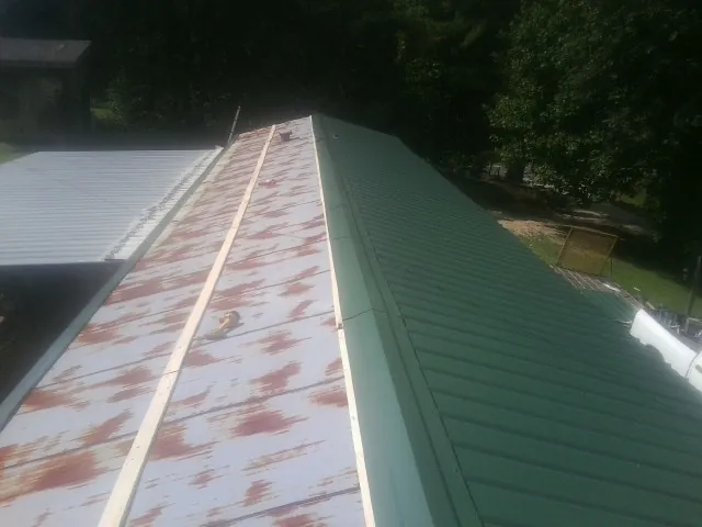 Old rusted panels beside newly installed green metal roofing — Wind Damage Roof Repair by Roofing Brothers in Terre Haute