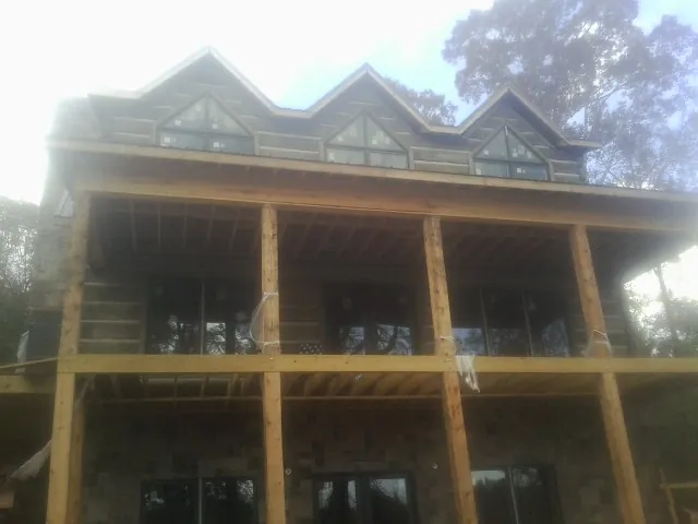Dormers and porch framing on a large log home under construction — Roof Coating work by our crew in Terre Haute