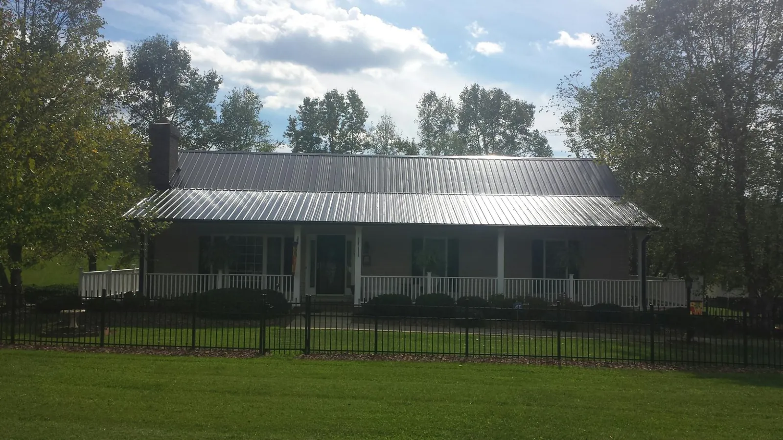 Gray metal roof on a brick ranch with a full width front porch — Gutter Guard Installation work by our crew in Terre Haute