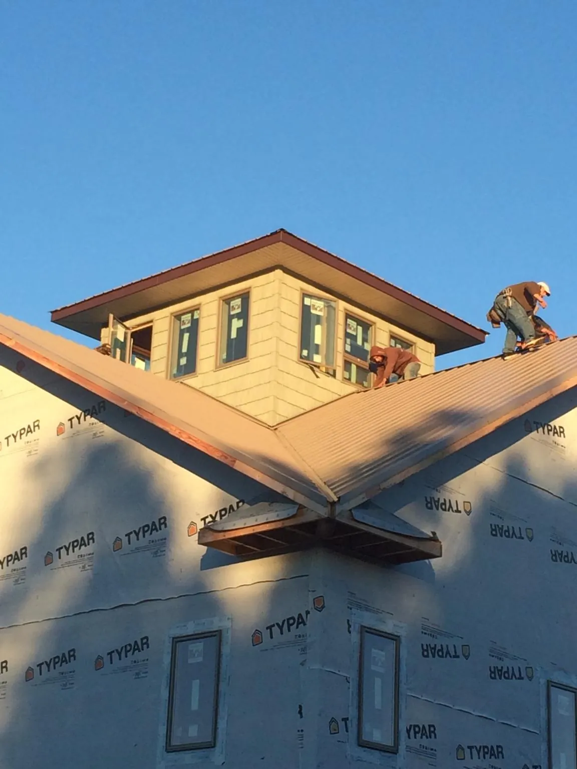 Roofers working around a rooftop cupola on a new metal roof at sunset — Roof Waterproofing in Terre Haute by Roofing Brothers